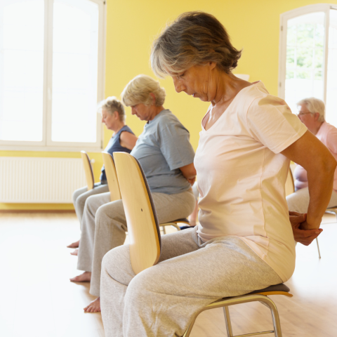 Women doing chair yoga in yellow room