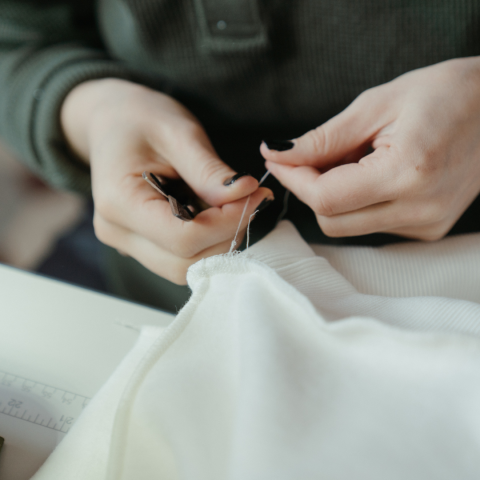 Person sewing at a machine, clipping thread