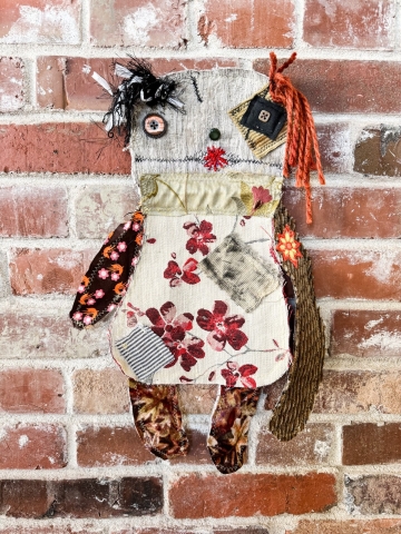 Hand-sewn doll against brick background