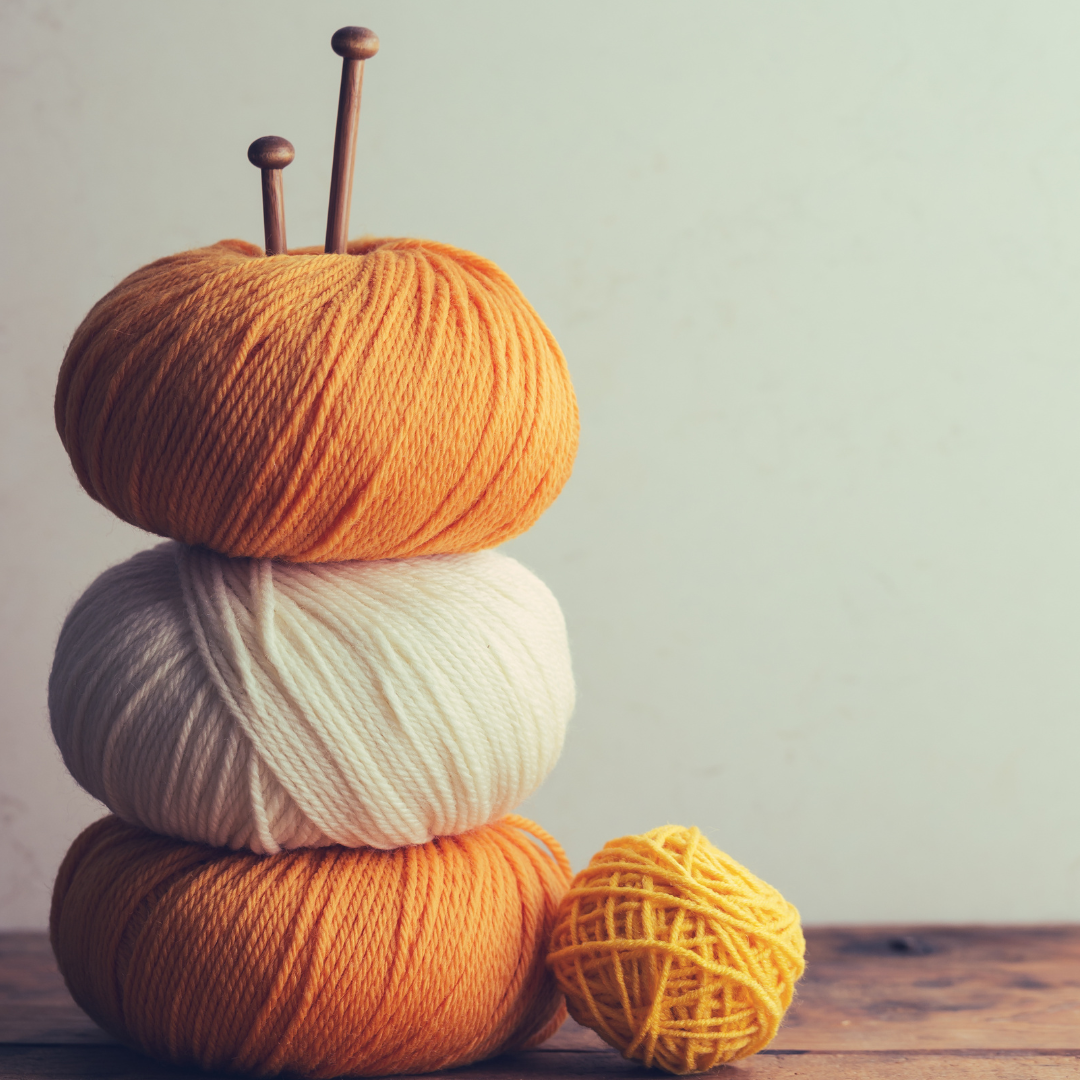 Stacked balls of yarn and a pair of knitting needles