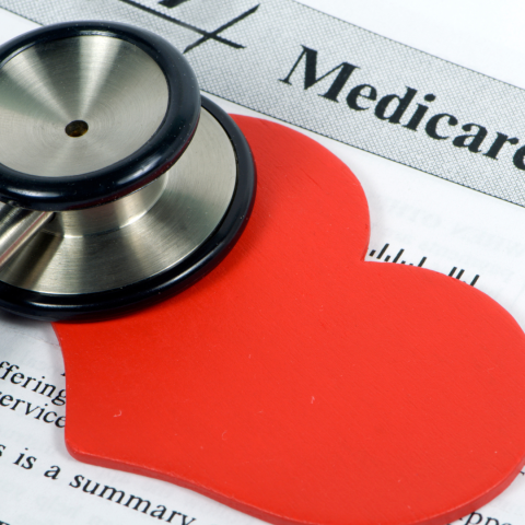 Red paper heart and stethoscope over Medicare form